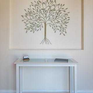 A minimalist interior featuring a console table and wall art depicting a tree.