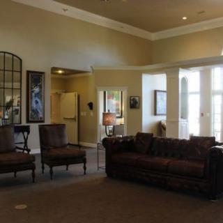 A well-furnished living room with a sofa, chairs, and decorative artwork.