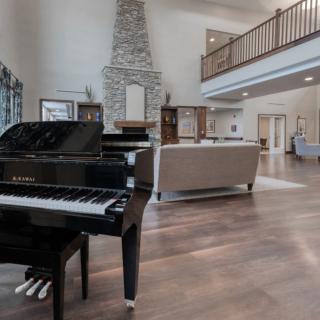 Modern living room with a grand piano and stone fireplace.