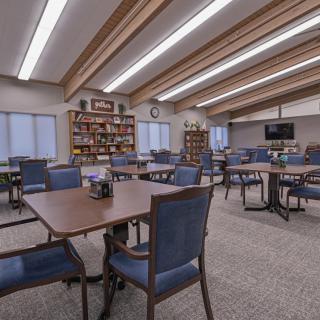 A spacious study area with numerous tables and chairs surrounded by bookshelves.
