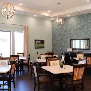 A well-lit dining room with several tables and chairs arranged neatly, featuring elegant lighting and decor.