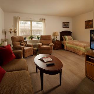 A cozy living and bedroom area featuring comfortable seating, a television, and a bed.