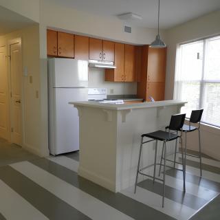 A modern apartment kitchen with a small breakfast bar and two bar stools.