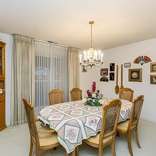 A classic styled dining room featuring a large table with six chairs and a chandelier above.