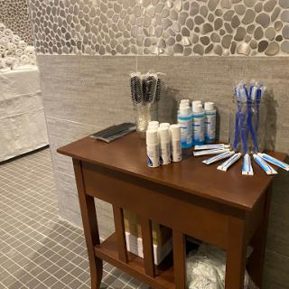 A neatly arranged bathroom amenities station featuring toiletries and toothbrushes on a wooden table.