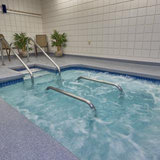 An indoor hot tub with bubbling water, surrounded by tiled walls and equipped with metal stairs for easy access.