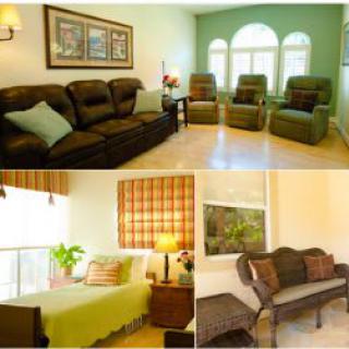 A cozy living space featuring a living room with recliner chairs and a sofa, alongside a bedroom with vibrant decor.