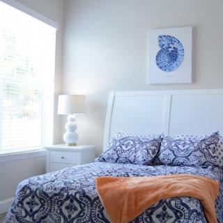 A cozy bedroom with patterned bedding and a decorative wall art.