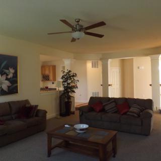 A cozy living room with two sofas, a coffee table, a ceiling fan, and wall artwork.