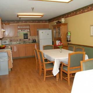 A cozy kitchen and dining area with a wooden table and chairs, featuring a refrigerator and cabinets.