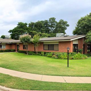 A suburban house with a well-maintained lawn and surrounding trees.