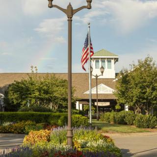 An outdoor shopping center with a landscaped garden and an American flag flying in front of the main building.