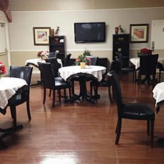 An empty dining room with tables and chairs, featuring a TV on the wall.
