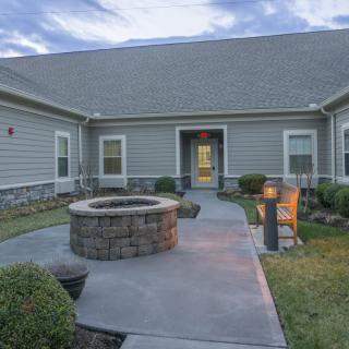 A modern house with a spacious yard featuring a fire pit and landscaping.