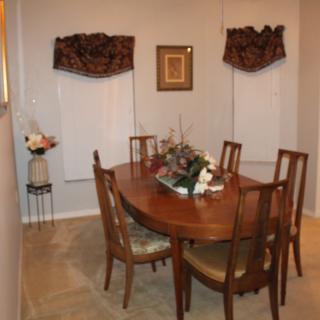 A cozy dining room with a wooden table and chairs, adorned with floral arrangements and tasteful wall decor.
