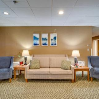A cozy living room with a beige sofa, blue armchairs, and warm lighting.