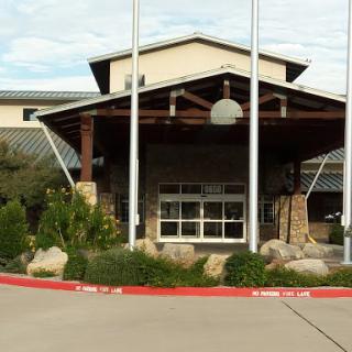 A welcoming entrance to a commercial building with landscaped surroundings and flag poles.