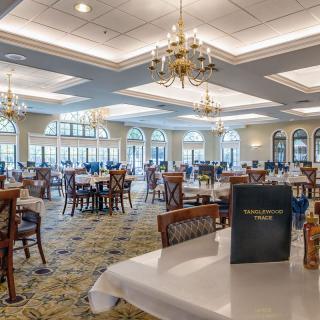 A spacious and elegantly decorated restaurant dining room featuring chandeliers and neatly arranged tables and chairs.