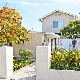 A residential house with a garden and trees in the front yard.