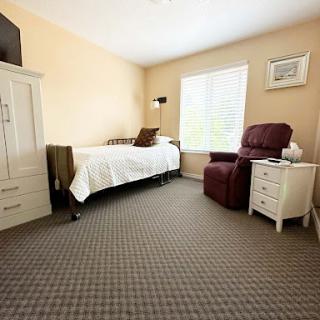 A cozy and well-lit bedroom featuring a single bed, armchair, and tasteful decor.