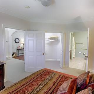 A cozy bedroom interior with a view of an adjoining room and bathroom through open doors.