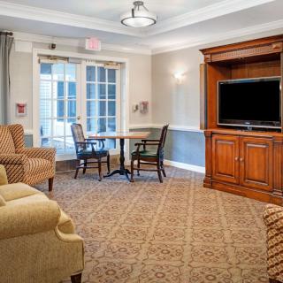 A cozy living room featuring comfortable seating, a table, chairs, and a large TV.