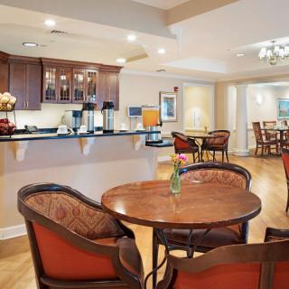 A cozy dining area with round tables and upholstered chairs, adjacent to a kitchen counter.