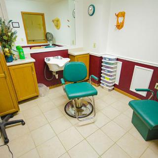 An interior view of a hair salon with a green barber chair and a wash basin.