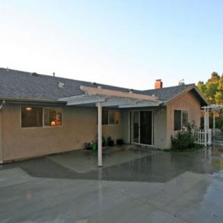 A view of a single-story house with a covered patio in the backyard.