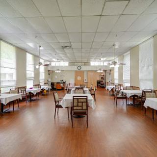A spacious and well-lit dining room featuring neatly arranged tables and chairs, showcasing a warm and inviting atmosphere.
