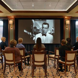 An audience enjoying a black and white film screening in a cozy indoor setting.