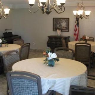 A well-decorated dining room with round tables, chairs, chandeliers, and an American flag in the corner.