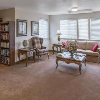A cozy and elegantly furnished living room with a sofa, armchair, bookshelf, and a coffee table.