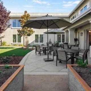 A well-maintained backyard patio featuring outdoor furniture and an umbrella, surrounded by a landscaped garden.