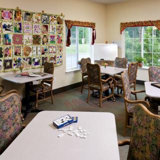 An empty classroom with tables and chairs, decorated with colorful artwork on the walls.