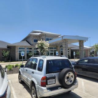 A modern building with a well-maintained exterior and vehicles parked in front.