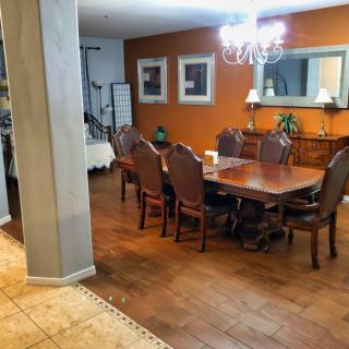 A cozy dining room with a large wooden table set and an elegant chandelier.