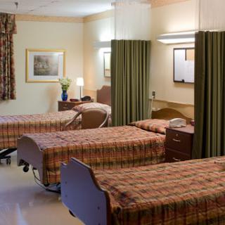 A well-arranged patient room in a healthcare facility, featuring multiple beds and privacy curtains.
