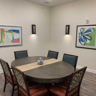 A modern dining room with a round table, six chairs, and abstract artwork on the walls.