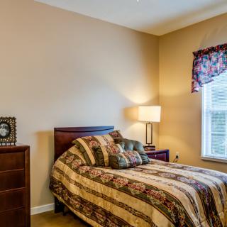Cozy bedroom with a patterned bedspread and warm lighting.