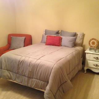A cozy bedroom with a comfortable bed, decorative pillows, and a side table with a lamp.