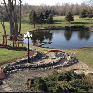 A serene park view featuring a tranquil pond, lush greenery, and a winding stone pathway.
