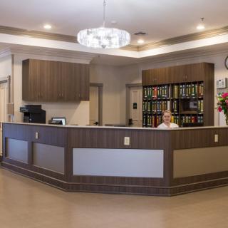 A modern reception desk in an office lobby with organized shelving and contemporary lighting.