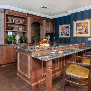 A stylish kitchen with wooden cabinets, a marble countertop, and barstools, complemented by decorative elements and artwork on the walls.