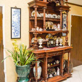 A beautifully crafted wooden shelf adorned with ceramics and decorative items, accompanied by a lush indoor plant.