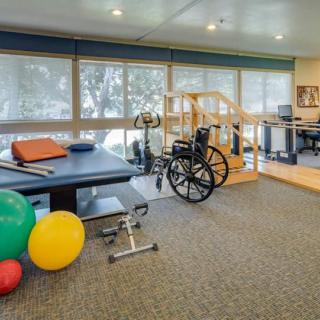 A rehabilitation room equipped with exercise gear and a wheelchair, designed for physical therapy sessions.