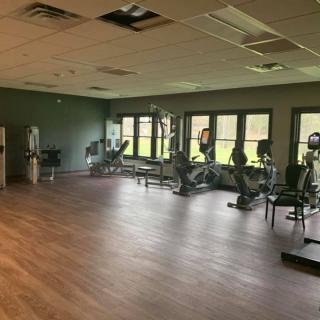 An empty gym with exercise equipment and large windows.