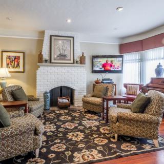 A cozy living room with a fireplace, armchairs, and a television.