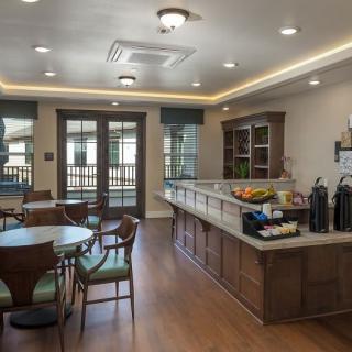 Cozy cafe interior with wood flooring, a coffee station, and seating arrangement.