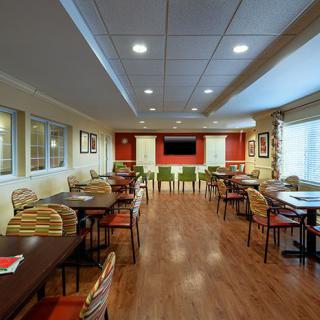 A cozy dining area with wooden flooring and arranged tables and chairs.